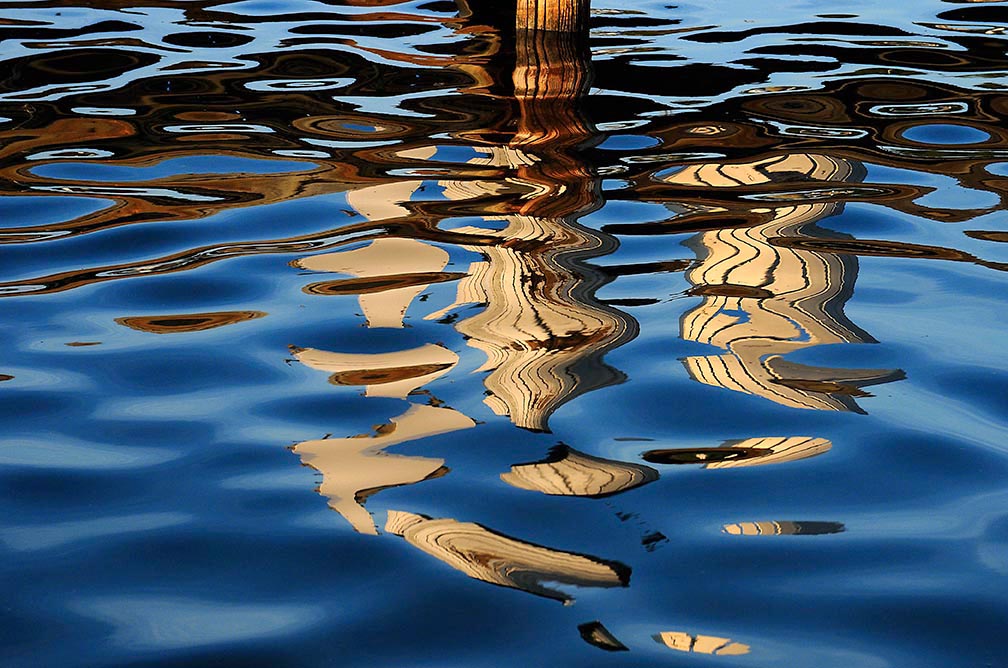 reflection of a dock makes artistic patterns on wavy water
