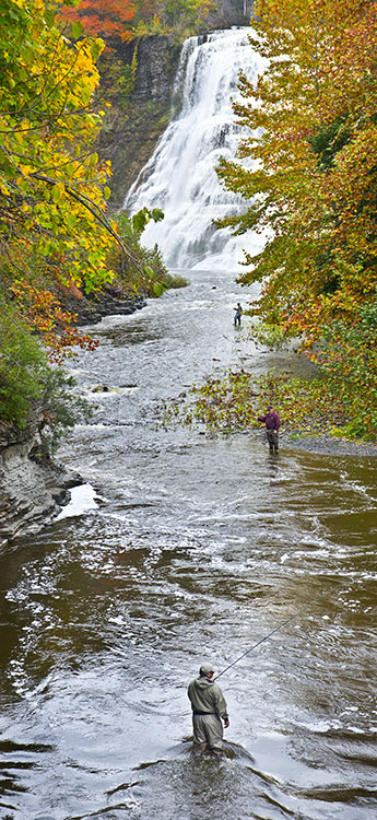 Three fishermen try their luck in Fall Creek with Ithaca Falls in the background