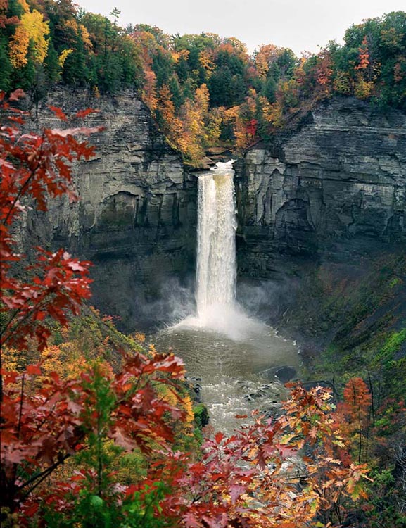 Taughannock Falls sprays mist while surrounded by colorful autumn foliage